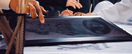Professionals engage in a collaborative engineering project, using a digital tablet and blueprints....