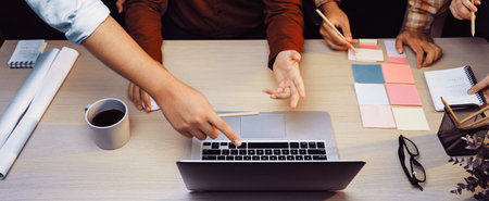 A diverse team engaged in an interactive meeting, showcasing hands gesturing over a laptop with...