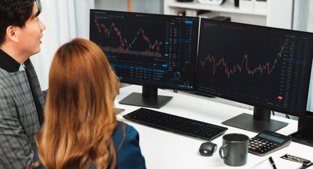 Panoramic photo of analyzing Asian businesswoman looking dynamic stock exchange data on two screens...