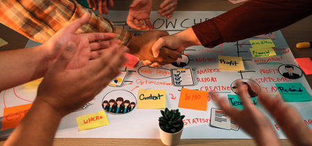 Diverse hands come together in a collaborative meeting, shaking hands over an insightful flowchart,...