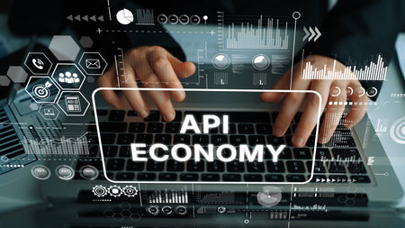 Hands Typing on Laptop with Overlaid Graphics Representing the Concept of API Economy in Digital...
