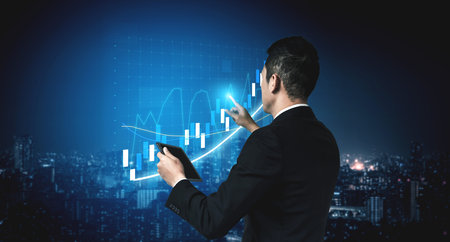 A business professional stands against a city skyline at night, analyzing financial data on a...