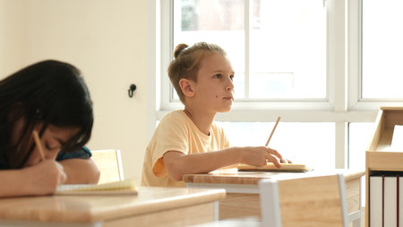 Smart student answer teachers question while sitting at classroom. Diverse children learning and...