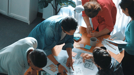 Top view of smart civil engineer looking project plan at meeting table while design building...