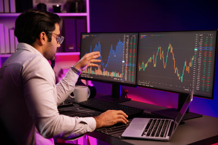 Smart trader businessman concentrating on dynamic stock exchange investment on pc and laptop showing...