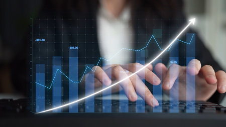 A business professional focuses on analyzing data and trends using digital graphs and charts,...