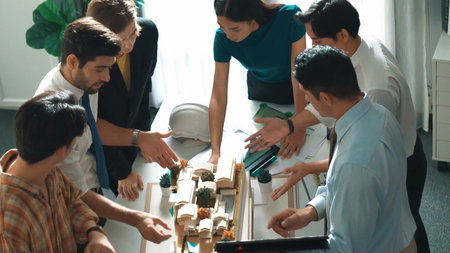 Professional architect engineer sitting while explaining house plan to manager. Aerial view of smart designer looking at blueprint while talking about building construction at meeting room.の写真素材