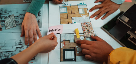 A group of individuals collaborates on interior design plans, showcasing hands selecting color samples and discussing layout details over blueprints and design visuals.の写真素材