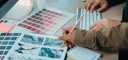 A modern workspace features hands examining color swatches and design materials. A functional setup...