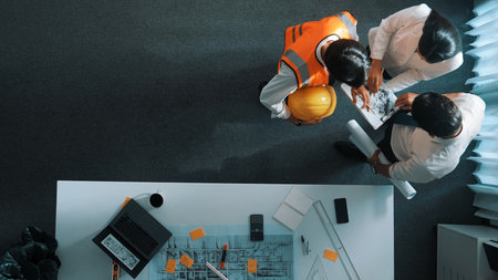 Top view of skilled architect engineer team looking at blueprint together. Aerial view of smart...