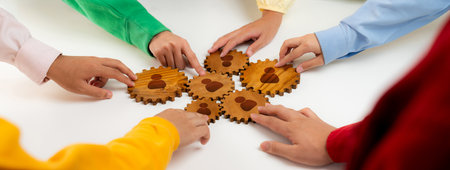 Diverse hands come together to connect gears, symbolizing teamwork and networking in a professional environment. Ideal for concepts surrounding collaboration and innovation. Amityの写真素材