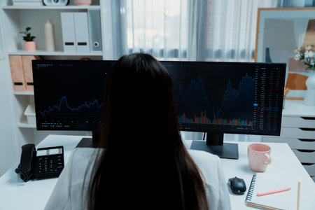 Young beautiful Asian businesswoman looking on pc to analyze profitable of exchange stock market graph at modern office. Concept of investing high profit in wealth security in finance. Stratagem.の写真素材