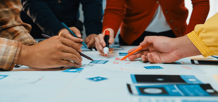 Diverse hands engaged in planning and designing digital solutions during a collaborative brainstorming session, showcasing teamwork and creativity in a modern workspace.の写真素材