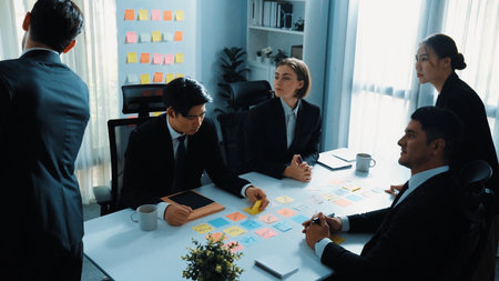 Top view of smart businessman putting sticky note on whiteboard while marketing team brainstorm creative idea at meeting room. Leader explain startup project to group of diverse investor. Directorate.の写真素材