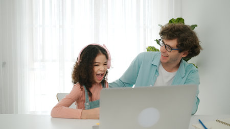 Caucasian dad put headphones on daughter while girl learning code. Father take care schoolgirl while...