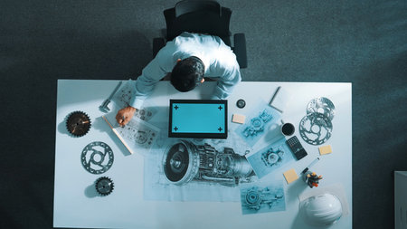 Top view of skilled engineer writing in paper while looking at tablet display green screen with...