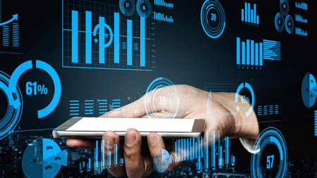 A hand holding a smartphone surrounded by digital analytics and business data. The image captures...