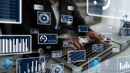 A person types on a laptop while surrounded by digital data visualizations. This image represents...