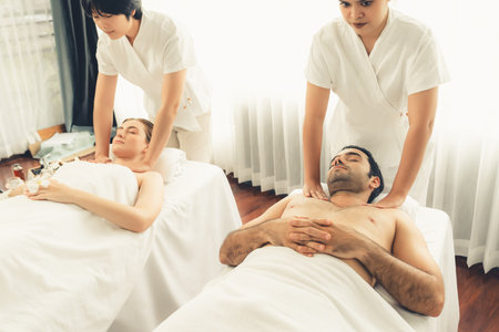 Caucasian couple customer enjoying relaxing anti-stress spa massage and pampering with beauty skin recreation leisure in day light ambient salon spa at luxury resort or hotel. Quiescentの写真素材
