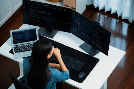 Top view young IT developer creating with typing online information on pc with coding program data of website application, wearing jeans shirt. surround by safety analysis two screen.の写真素材