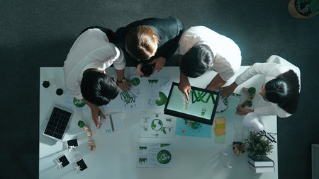 Top view of manager hold tablet display clean energy investment at meeting. Aerial view of skilled business team working together and planning to use sustainability environmental energy.の写真素材