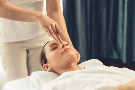 Caucasian woman enjoying relaxing anti-stress head massage and pampering facial beauty skin recreation leisure in dayspa modern light ambient at luxury resort or hotel spa salon. Quiescentの写真素材