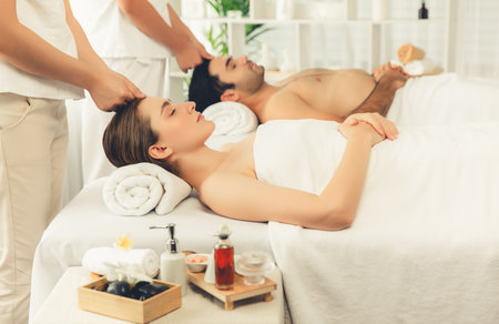 Caucasian couple enjoying relaxing anti-stress head massage and pampering facial beauty skin recreation leisure in dayspa modern light ambient at luxury resort or hotel spa salon. Quiescentの写真素材