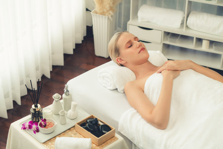 Caucasian woman customer enjoying relaxing anti-stress spa massage and pampering with beauty skin recreation leisure in day light ambient salon spa at luxury resort or hotel. Quiescentの写真素材