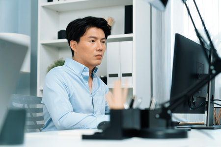Serious smart businessman working on computer to check email with business project report, analyzing on market shares customer database in casual day at modern office in startup concept.の写真素材