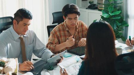Top aerial view of project manager or civil engineer writing at blueprint and planning building design. Aerial view of architect working together at meeting table with document placed.の写真素材