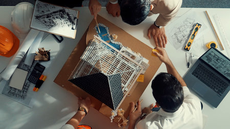Top down aerial view of smart architect engineer team inspect house model while manager hold blueprint and asking about building construction. Group of diverse engineer working together.の写真素材