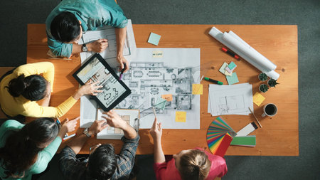 Top down aerial view of smart engineer looking at blueprint at meeting room. Skilled architect team talking and discussing while inspecting at project plan at meeting table with blueprint. Symposium.の写真素材