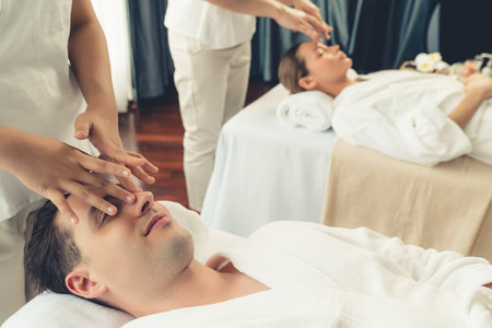 Caucasian couple enjoying relaxing anti-stress head massage and pampering facial beauty skin recreation leisure in dayspa modern light ambient at luxury resort or hotel spa salon. Quiescentの写真素材