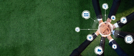 Aerial view of hands joining together on green grass, symbolizing collaboration and partnership in a...