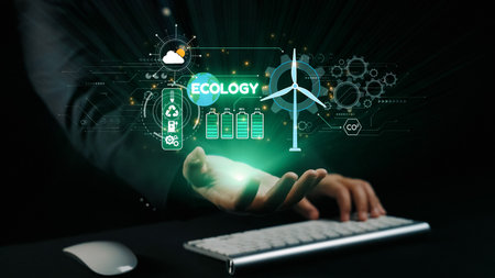 A hand positioned near a computer keyboard displays an innovative ecology concept, showcasing sustainable energy symbols like wind turbines and battery icons against a dark background.の写真素材