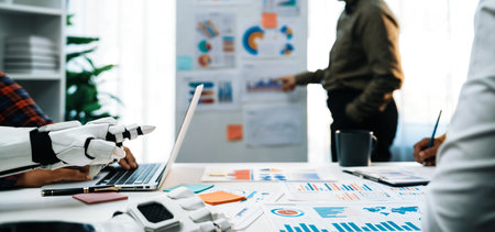 A modern office scene depicting a robot hand assisting in data analysis, showcasing charts and reports. The environment highlights collaboration, innovation, and technology.の写真素材