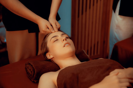 Caucasian woman enjoying relaxing anti-stress head massage and pampering facial beauty skin recreation leisure in warm candle lighting ambient salon spa in luxury resort or hotel. Quiescentの写真素材