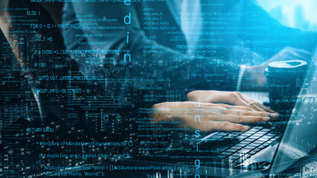 A close-up view of hands typing on a laptop amidst an overlay of programming code, showcasing the...