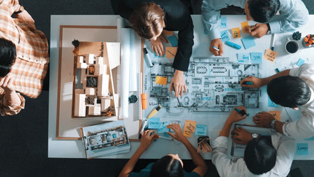 Top aerial view of project manager or civil engineer writing at blueprint and planning building design. Aerial view of architect working together at meeting table with document placed.の写真素材
