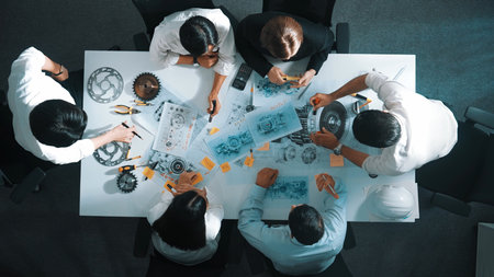 Top down view of skilled engineer showing and talking about turbine engine design. Aerial view of skilled designer or technician group explain about electronic generator construction. Alimentation.の写真素材