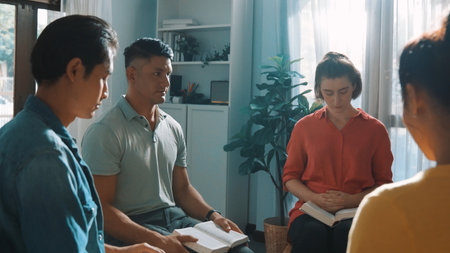 Top view of skilled diverse prayer clasping hand and praying to god while sitting at chair in circle. Top down aerial view of people folded hand while sitting with opened bible on laps. Symposium.の写真素材