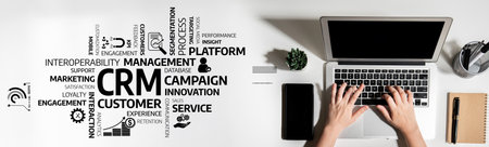 Aerial view of hands typing on a laptop in a modern office, surrounded by CRM-related keywords and concepts, emphasizing business management and customer engagement. Tesselの写真素材