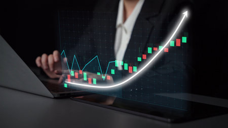 A business professional analyzes financial data through a laptop screen, displaying a stock market...
