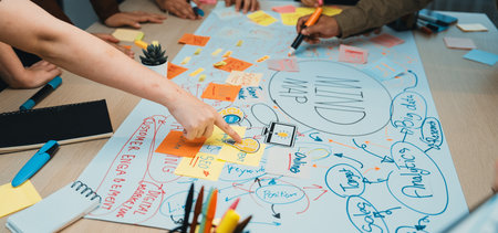 A dynamic group collaborates on a mind map using colorful sticky notes in a bright office setting,...