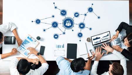 A diverse team collaborates at a modern office table surrounded by digital media and data...