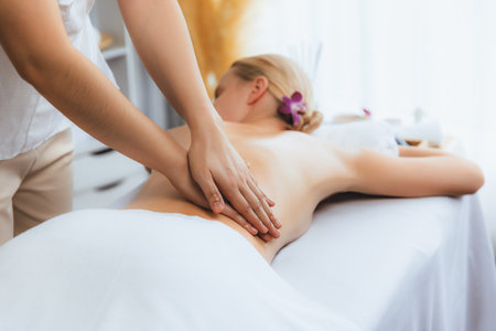 Caucasian woman customer enjoying relaxing anti-stress spa massage and pampering with beauty skin recreation leisure in day light ambient salon spa at luxury resort or hotel. Quiescentの写真素材