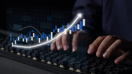 Close-up of hands typing on a keyboard with an overlay of financial graphs, illustrating the data...