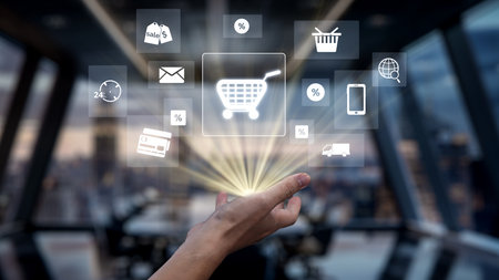 A hand reaches toward a glowing shopping cart icon surrounded by various e-commerce symbols,...