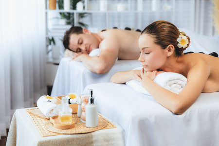 Hot stone massage at spa salon in luxury resort with day light serenity ambient, blissful couple customer enjoying spa basalt stone massage glide over body with soothing warmth. Quiescentの写真素材