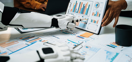 A futuristic robot arm showcases business charts while professionals engage in discussions. This scene highlights the intersection of technology and human collaboration in data analysis.の写真素材